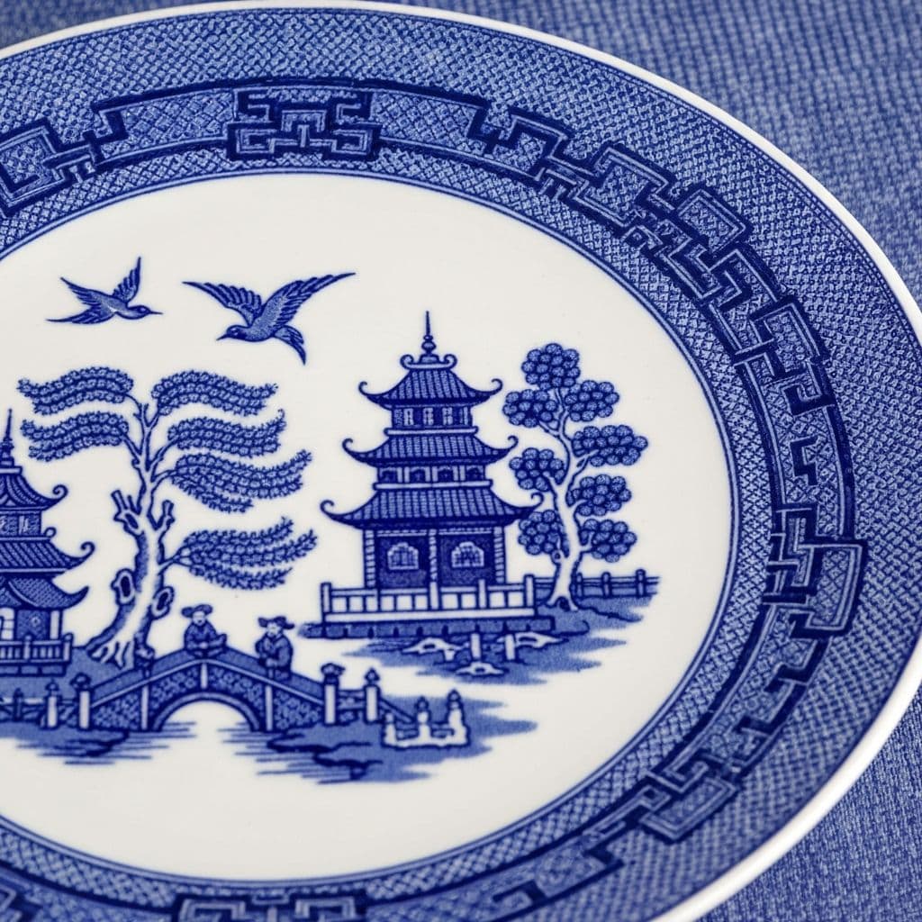 Close-up detail of the Blue Willow pattern showing the pagoda, willow tree, bridge, and birds